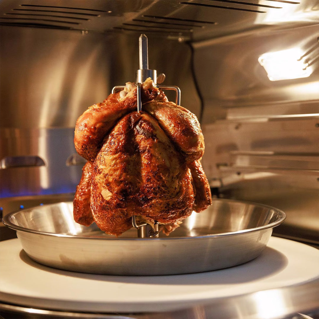 Roasted chicken on a rotisserie in a kitchen setting